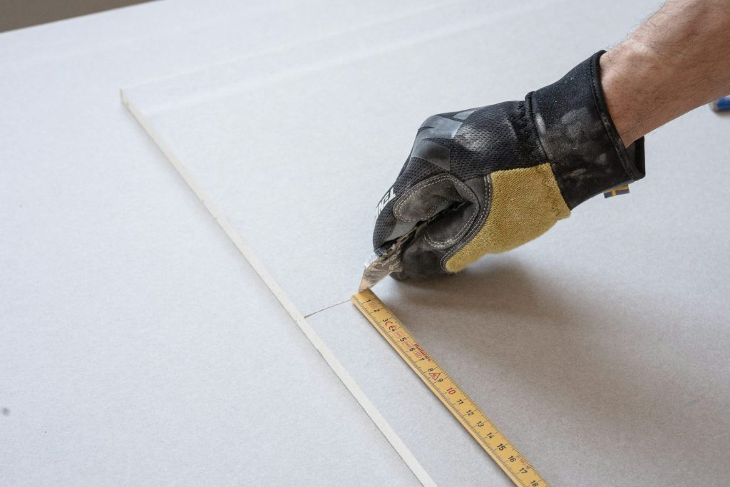 une personne mesurant un morceau de papier avec un ruban à mesurer