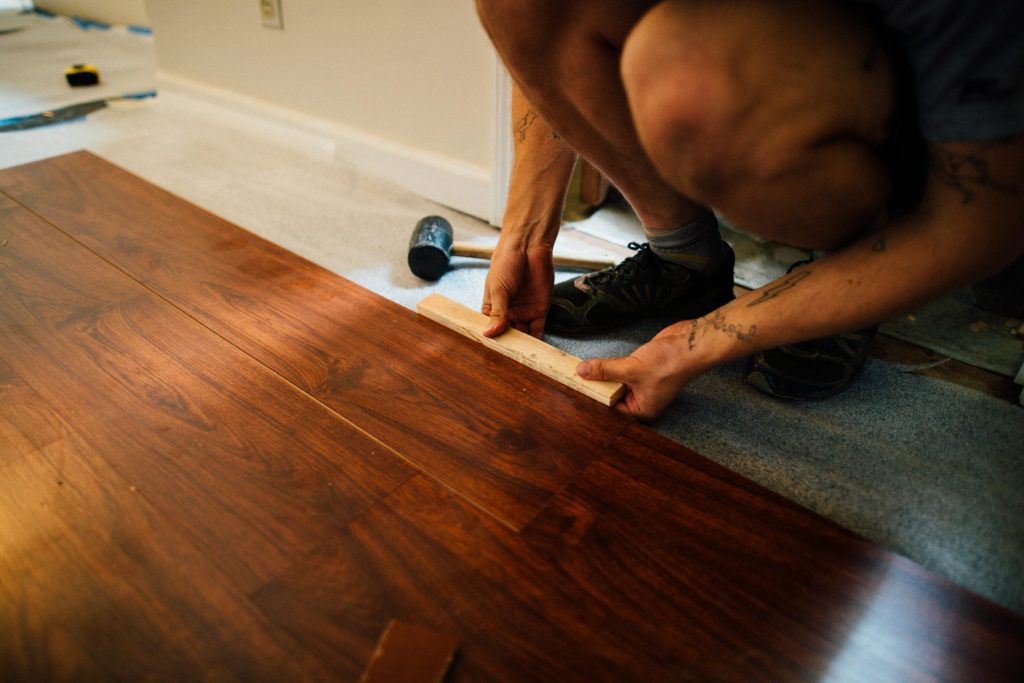 Un expert pose un parquet à l'intérieur, témoignant d'un savoir-faire précis et d'une rénovation intérieure moderne.