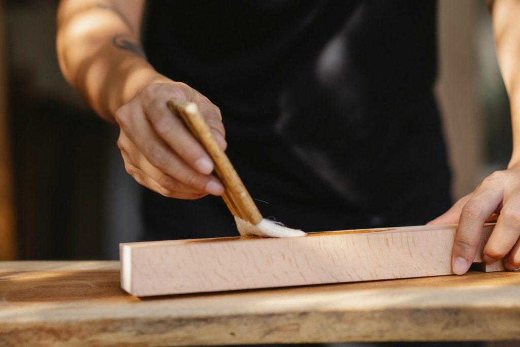 Un artisan applique soigneusement du vernis sur une surface en bois, faisant preuve d'un savoir-faire artisanal.